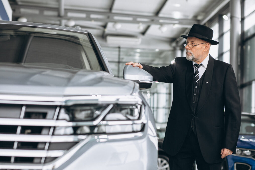 senior-man-car-showroom-choosing-car-scaled