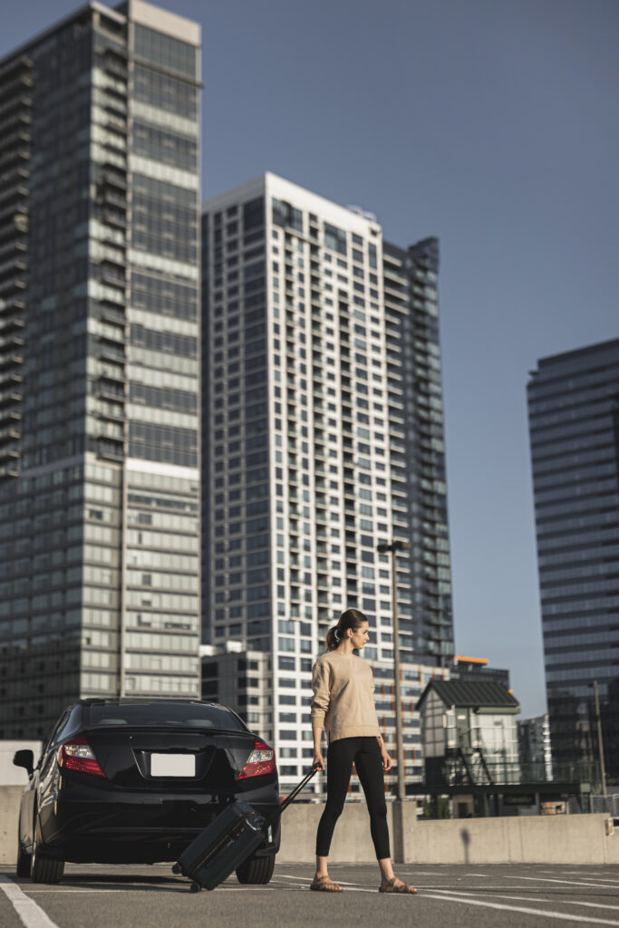young-woman-standing-with-suitcase-parking